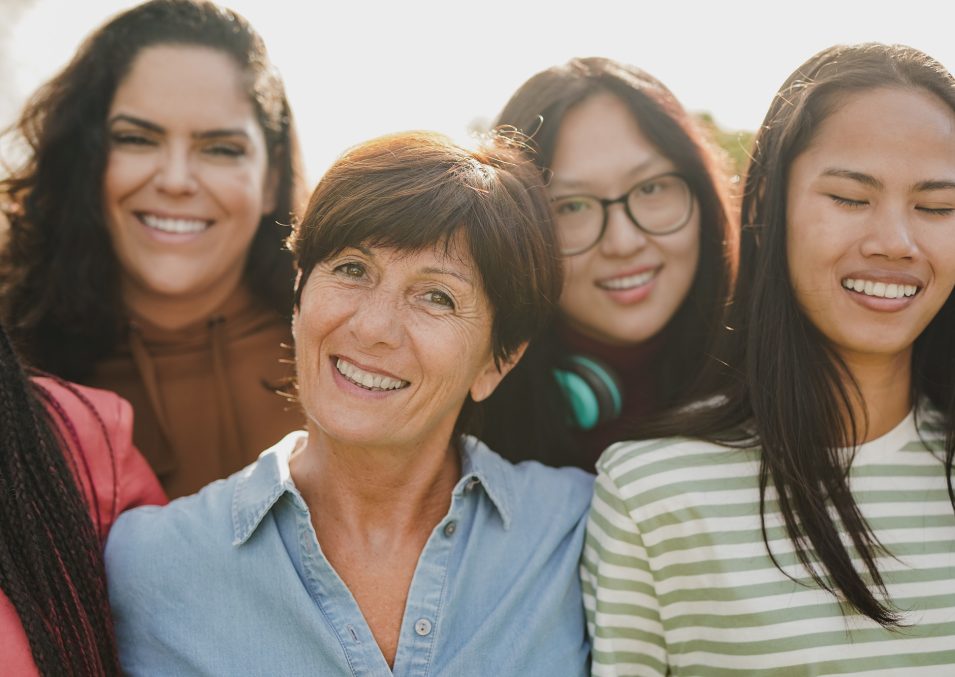 Group of multiracial women with different ages smiling in front of camera