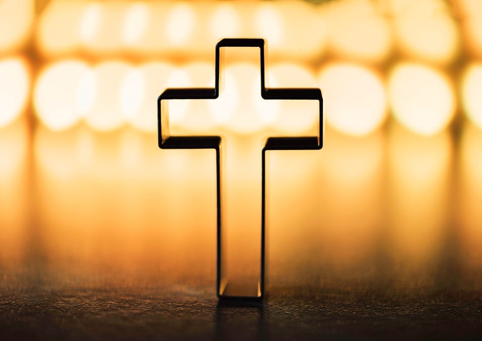 Silhouette of christian cross on yellow background, soft bokeh lights background. Copy space. Church